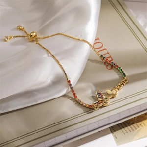 Détail du bracelet MOM avec zircons arc-en-ciel et un pendentif papillon doré élégant