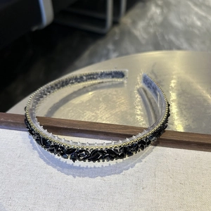 Close-up of Baroque crystal headband with black rhinestones on a beige textured fabric
