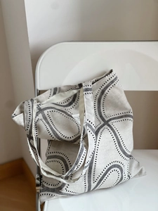 Detailed close-up of geometric printed tote bag hanging on a chair showing fabric texture