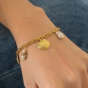 Bohemian gold chain bracelet with natural sea shells and fan scallop charm on wrist