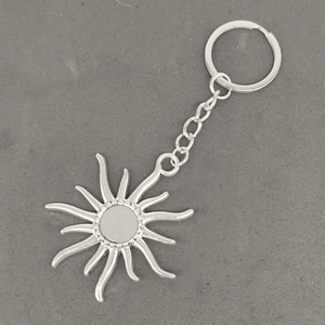 Detail of vintage silver sun and moon keychain with metallic link chain on concrete background
