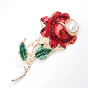 Detail of red rose brooch with green enamel leaves and large white pearl inlay