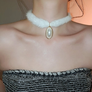 Detail of elegant white faux fur necklace with a gold-edged pearl pendant on model
