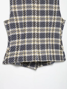 Gros plan sur la texture du tweed à carreaux bleu marine et jaune avec boutonnière