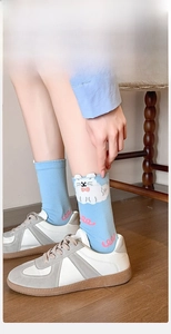Detail of light blue crew sock featuring 3D cartoon cat ears and pink wavy patterns
