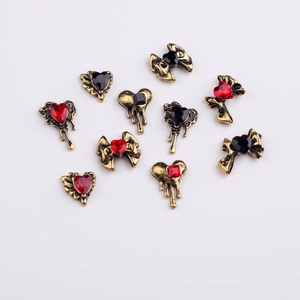 Detailed view of vintage gold nail charms featuring red and black heart and bow shapes