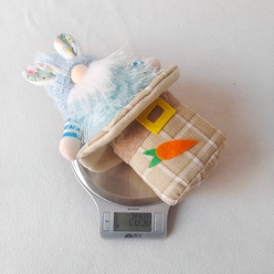 Detailed view of an Easter gnome plush on a scale showing a weight of 209 grams