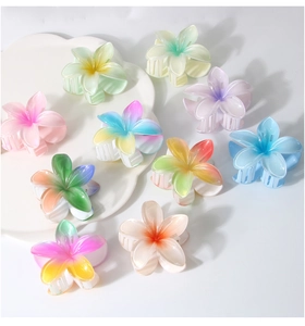 Detailed top view of large pearlescent gradient plumeria hair claws on a white tray