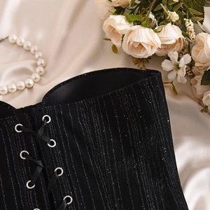 Detailed view of black sequin corset with silver eyelets and criss-cross lacing on satin