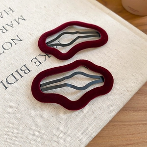 Detail showing the fine velvet texture and wavy design of the burgundy hair clips