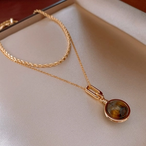 Detailed close-up of golden layered twist chain necklace with tiger eye stone pendant