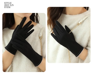 Detail view of black thermal gloves with elegant contrast stitching and plaid trim cuffs