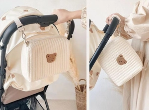 Detail of quilted stroller organizer bag with cute bear embroidery and metal hooks
