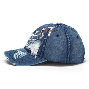 Close-up of distressed denim baseball cap with paint splatters and vintage embroidery