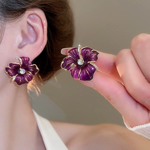 Vue détaillée d'une boucle d'oreille fleur en émail violet avec bords dorés et cristaux