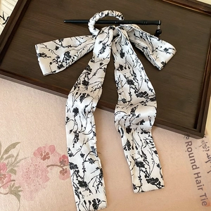 Close-up of silk ribbon with plum blossoms and black hairpin in a traditional tray
