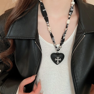 Close-up of leopard print ribbon necklace with black heart and silver cross pendant