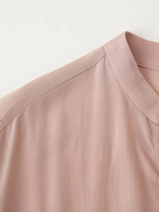 Dettaglio della camicetta in raso di seta rosa con elegante scollo a V e colletto