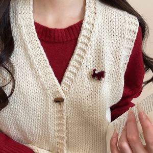 Detail of red flocked rocking horse brooch with pearls on a knitted sweater vest