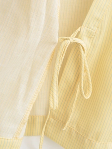 Detailed close-up of the yellow and white striped fabric with bow tie-waist detail