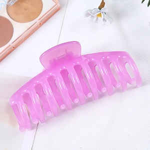 Top view of large translucent pink keel hair claw clip with spring on a white surface