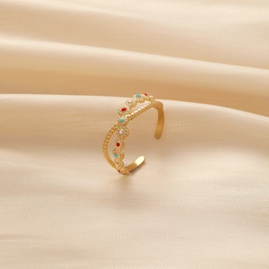 Macro detail of golden adjustable ring with colorful enamel flowers on silk background