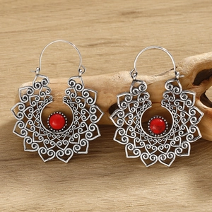 Detailed view of silver ethnic earrings with hollow heart pattern and red gemstone