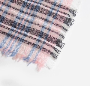 Detail of pink and blue plaid scarf showing fuzzy texture and fringe tassels on a white background