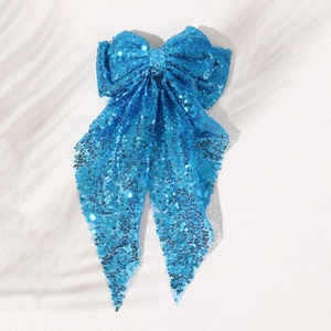 Detailed view of large blue sequin bow hair clip with long sparkling ribbons