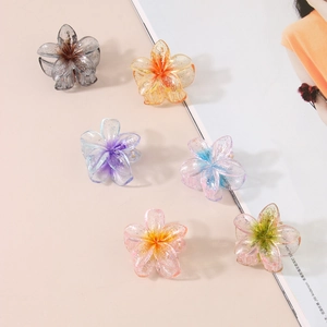 Set of 6 glitter transparent plumeria hair claws in various gradient colors on pink background