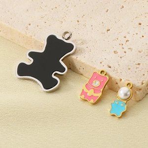 DIY stainless steel bear charms with colorful enamel and pearl accents on stone background