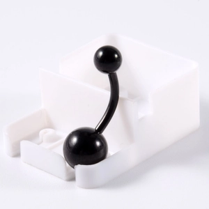Gros plan d'un piercing de nombril noir incurvé avec un design brillant à double bille