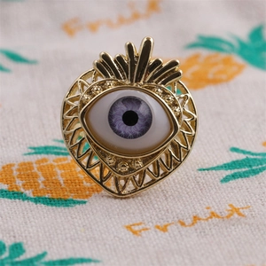 Macro shot of gold-plated evil eye ring with purple zircon stone on a patterned fabric