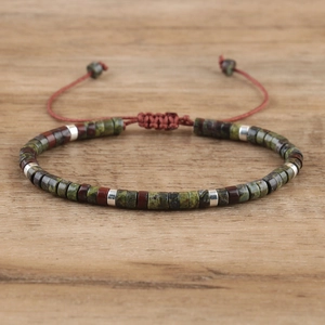 Macro detail of natural stone beads and silver spacers on handmade woven bracelet