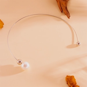 Détail d'un collier choker doré avec une perle large et une bille en métal