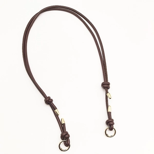 Close-up of adjustable brown leather bag strap with golden metal rings and knotted details
