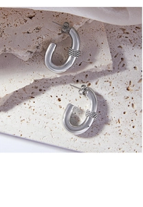 Detailed macro view of silver U-shaped twisted metal earrings on stone background