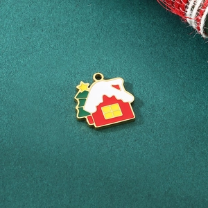 Detail of red Christmas house charm with green tree in enamel and gold stainless steel