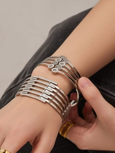 Dettaglio di bracciali con motivo ad albero e ampio bracciale geometrico con zirconi