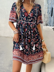 Detail of V-neck printed dress with navy floral pattern and bohemian fringe hemline