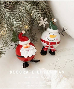 Festive Santa and Snowman iron ornaments placed under a Christmas tree with warm lights
