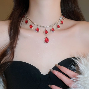 Detailed macro of a luxurious gold necklace with red teardrop gems on a model