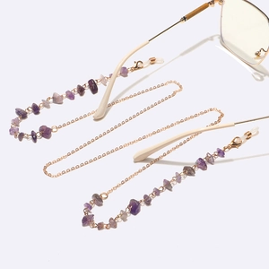 Macro shot of natural purple amethyst stones and gold chain links on an eyewear strap