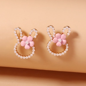 Macro shot of cute bunny stud earrings with white pearls and pink floral accents