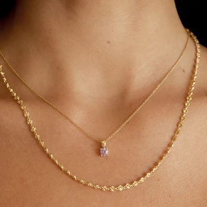 Detail of layered gold S925 silver necklaces with pink gemstone on female neck
