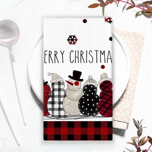 Christmas snowman kitchen towel with red black plaid pattern on a holiday dining table