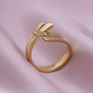 Close-up of geometric gold stainless steel ring with triple layered bars on purple silk