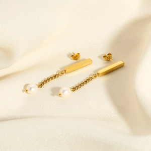 Detail von Goldketten-Ohrringen mit Balkendesign und weißer Süßwasserperle auf Seide