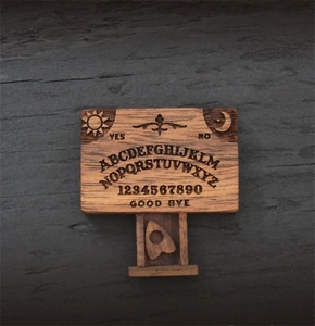 Detailed engraving on miniature wooden ouija board with planchette and sun moon motifs