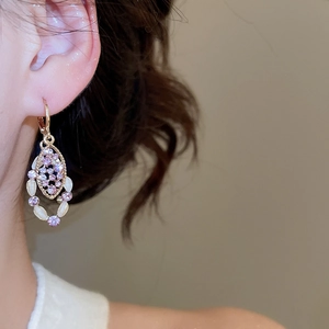 Detail of vintage style golden earrings with pink zircon and white marquise stones on model
